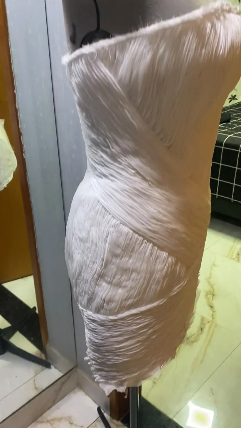 Tecido drapeado sobre manequim durante a criação de um vestido de noiva